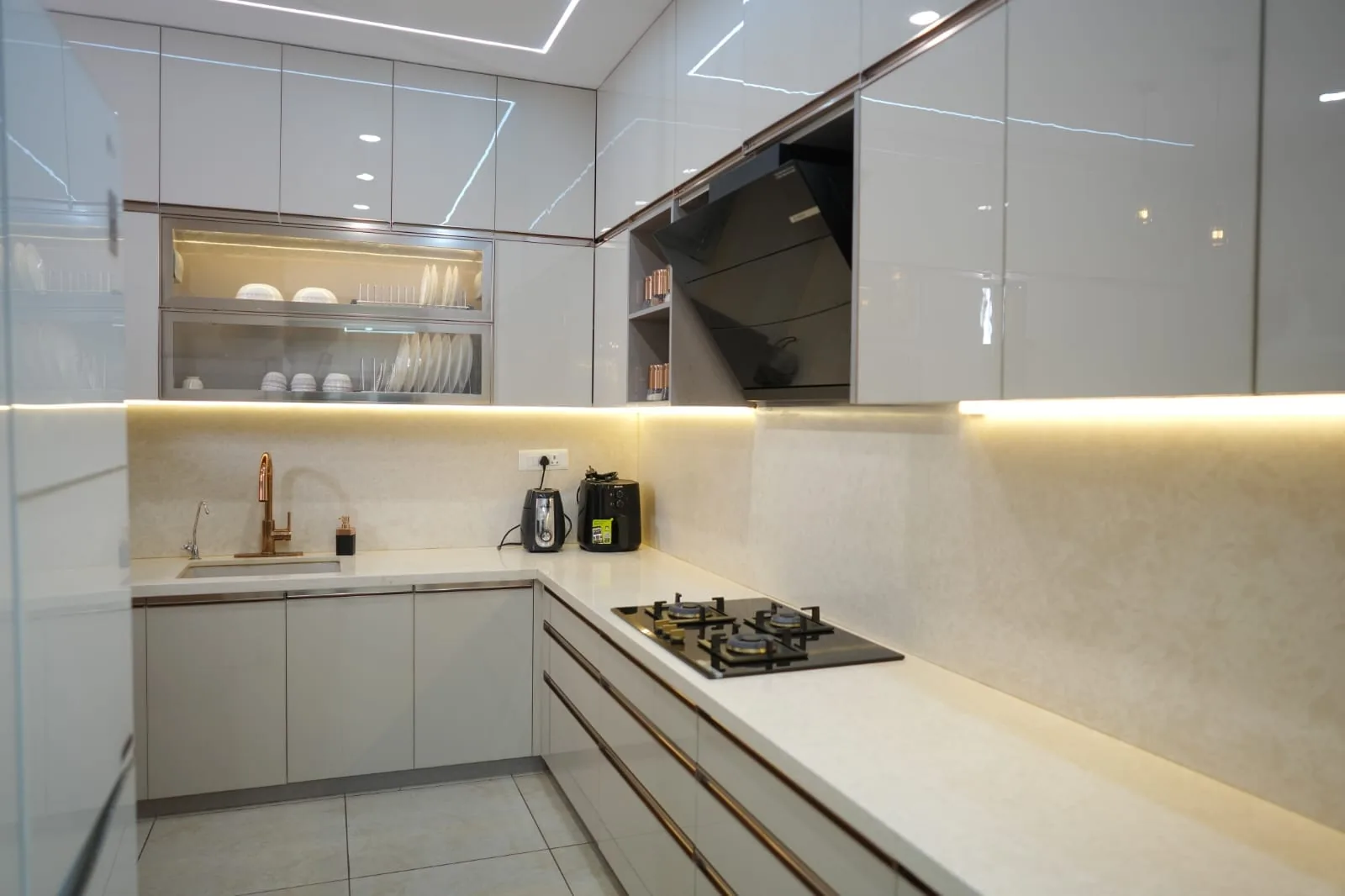 L-shaped glossy modular kitchen with under-cabinet lighting